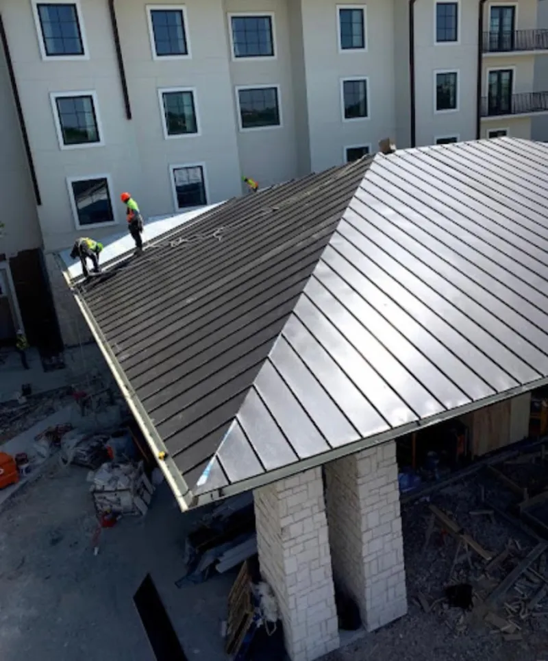 Crew installing standing seam metal roof panels on a commercial project in Fairburn
